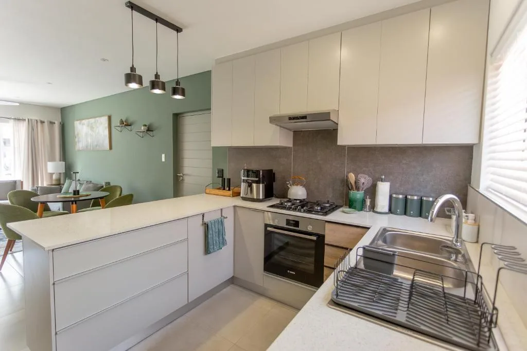 Modern kitchen with white cabinetry, stove, sink, and pendant lighting overhead