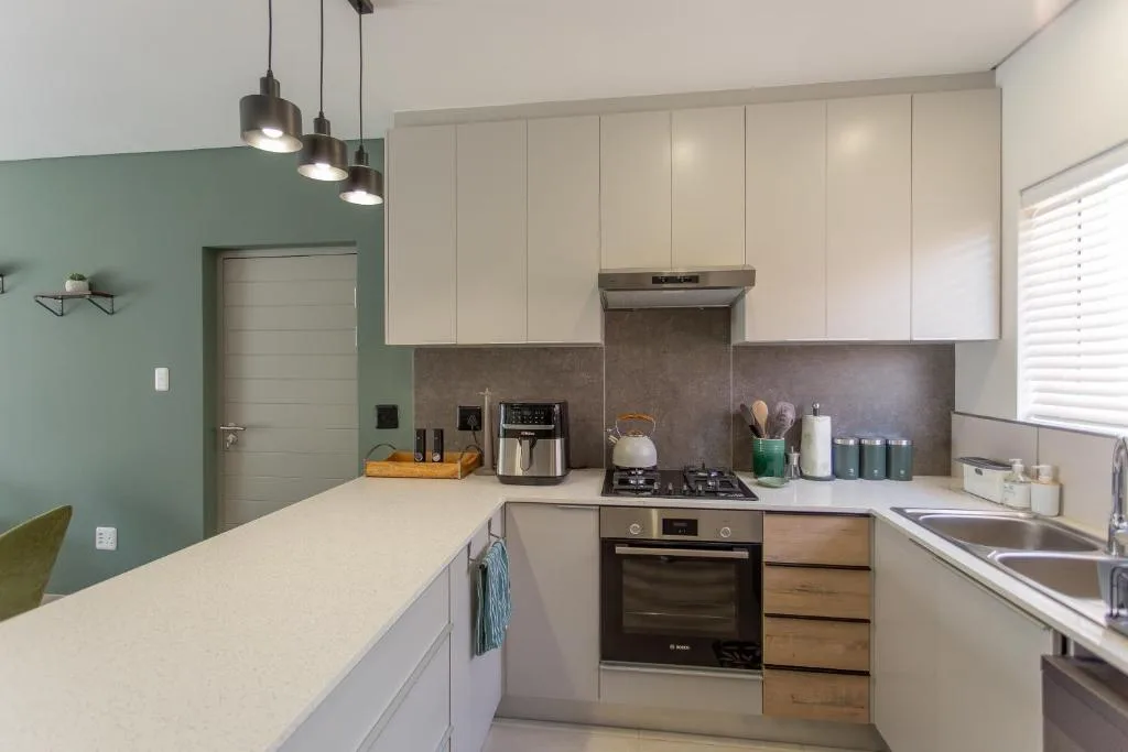 Modern kitchen with white cabinetry, stainless steel appliances, and gray backsplash