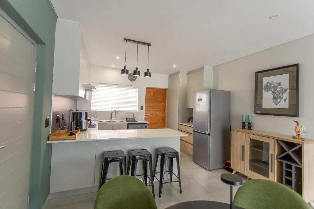 Modern open-plan kitchen with white cabinetry, stainless steel appliances, and island seating