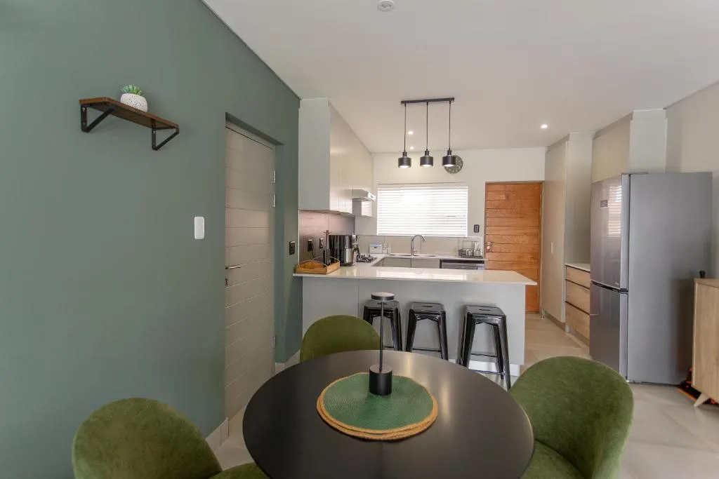 Modern kitchen with white counters, stainless steel appliances, pendant lights