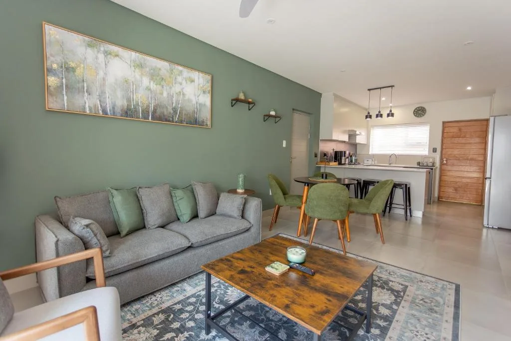 Modern lounge with gray sofa, wooden coffee table, green accent wall, and pendant lighting