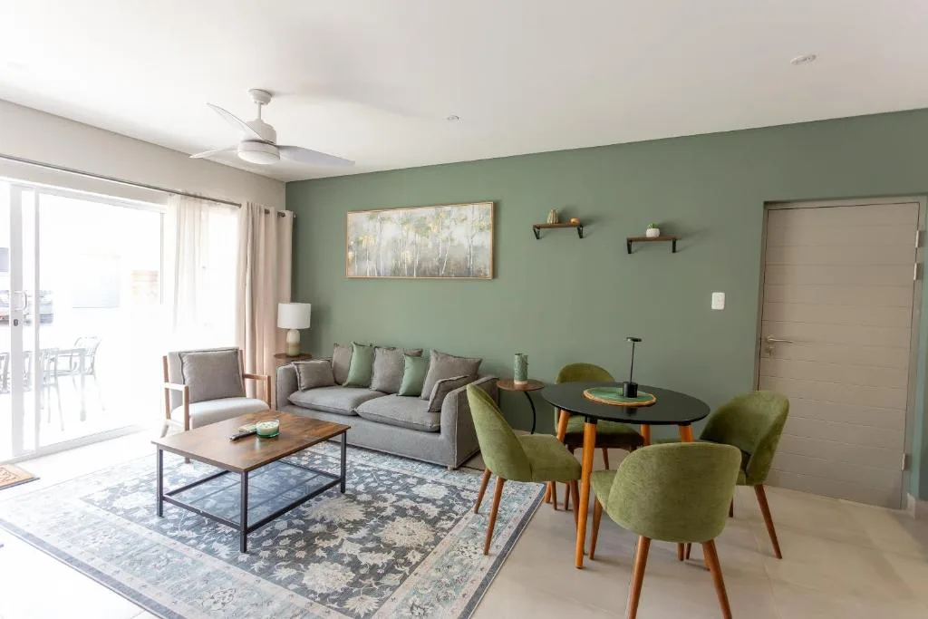 Bright lounge with sage green walls, grey sofa, and modern furniture