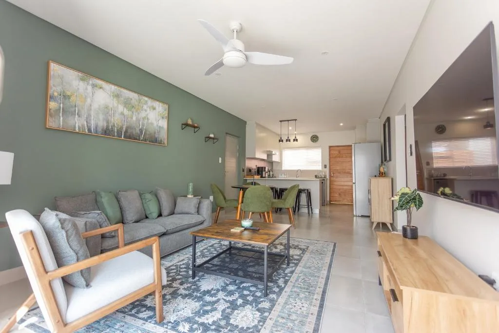 Open-plan lounge with gray sofa, wooden furniture, and green accent wall