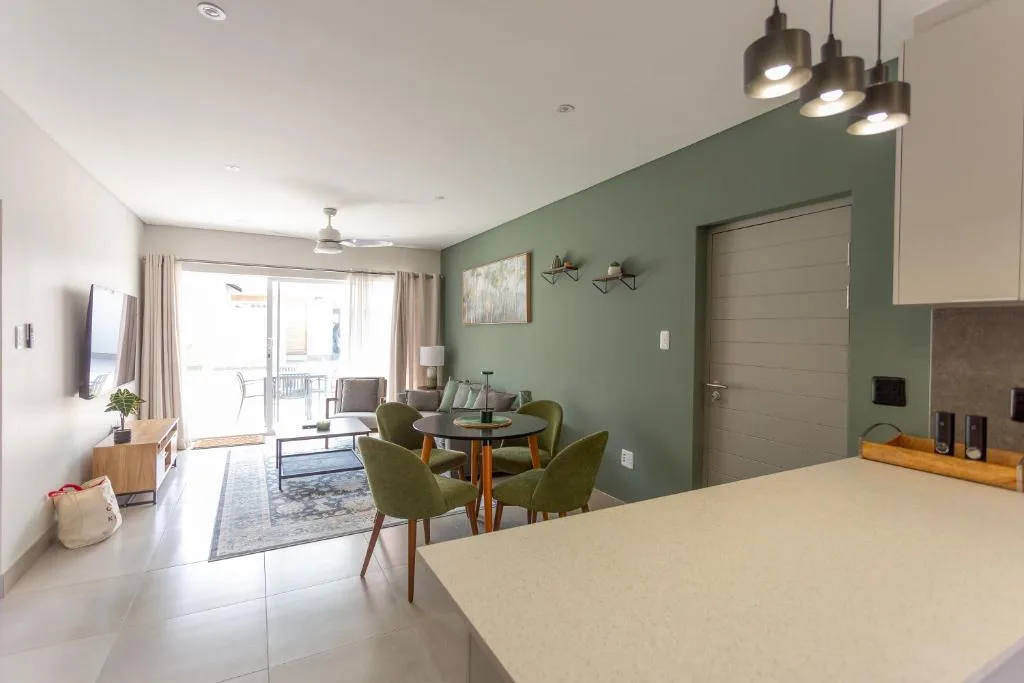 Modern open-plan lounge with sage green accent wall and dining area