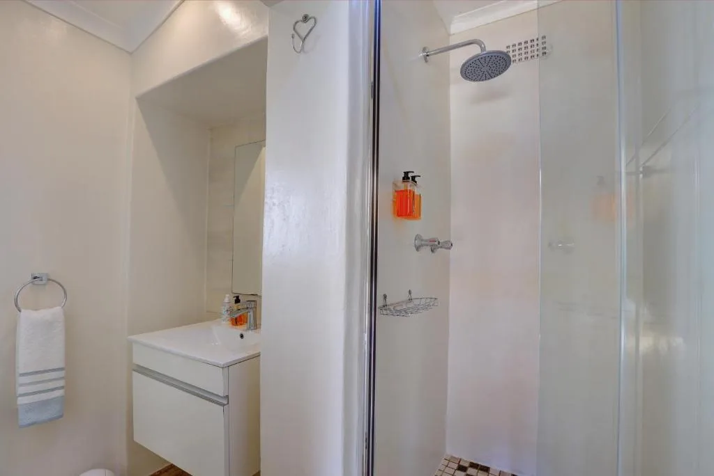 Modern white bathroom with vanity sink and walk-in shower enclosure