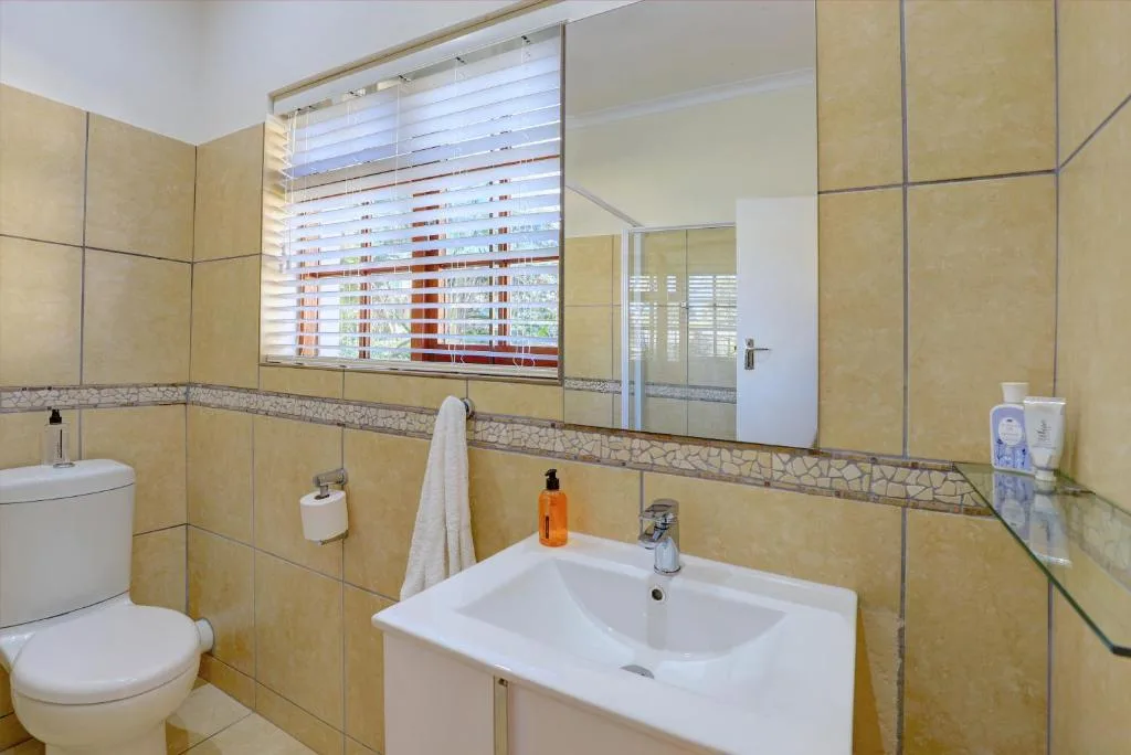 Modern bathroom with yellow tiles, vanity sink, and large mirror