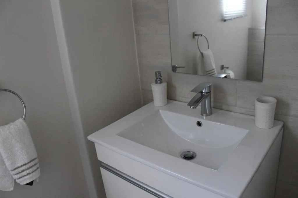 Clean white bathroom vanity with modern chrome tap and mirror