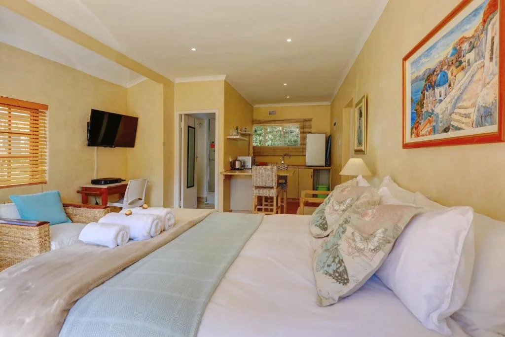 Spacious bedroom with twin beds, kitchenette, and mounted television