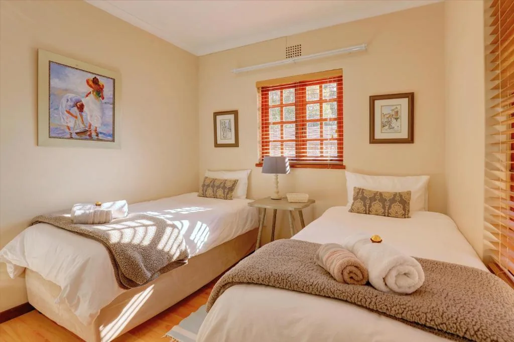 Bright twin bedroom with white beds, warm yellow walls, and rolled towels