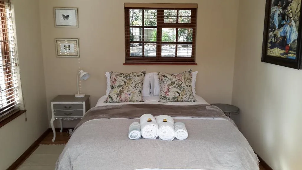 Bright bedroom with queen bed, floral pillows, and rolled towels displayed