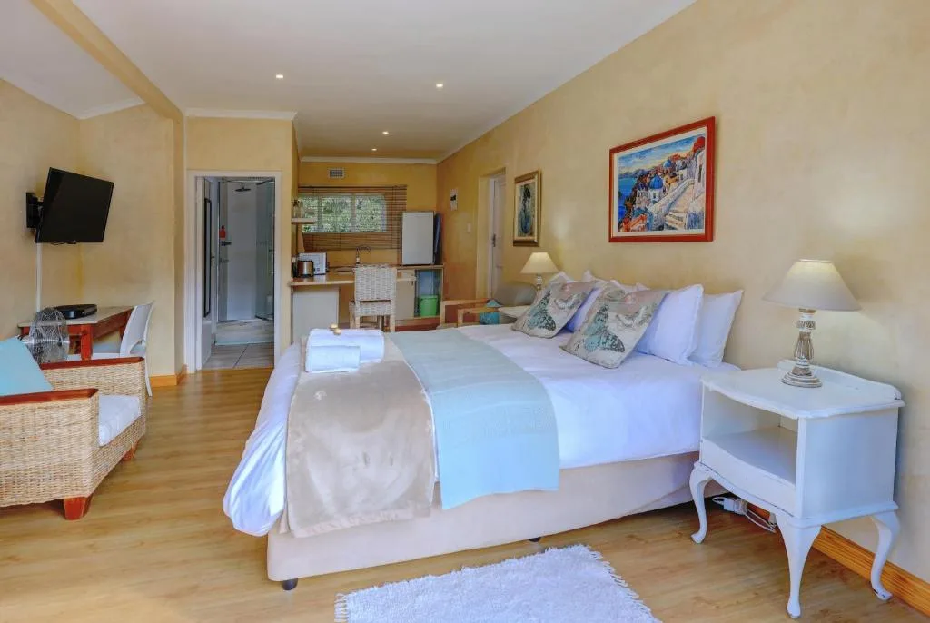 Spacious bedroom with queen bed, en-suite bathroom, kitchenette, and flat-screen TV