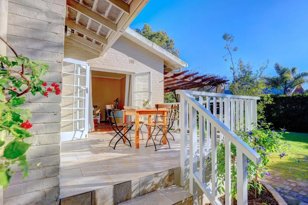 Wooden deck with dining table, white railings, and garden views