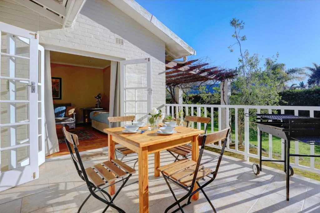 Wooden dining table and chairs on sunny patio with garden views