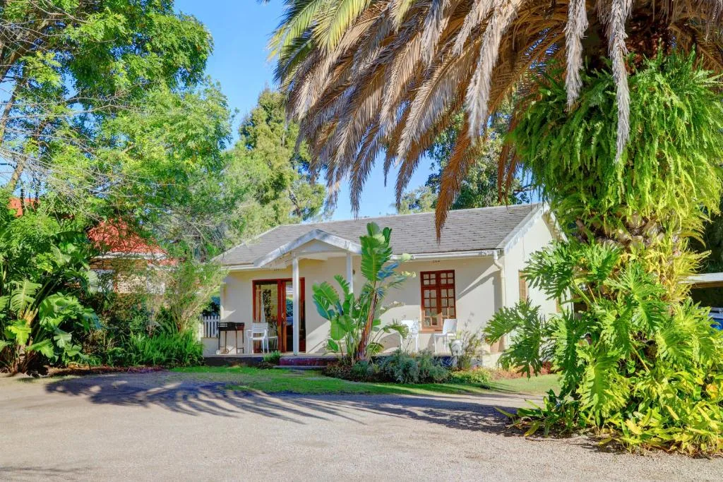 Charming white cottage with palm trees and lush garden landscaping