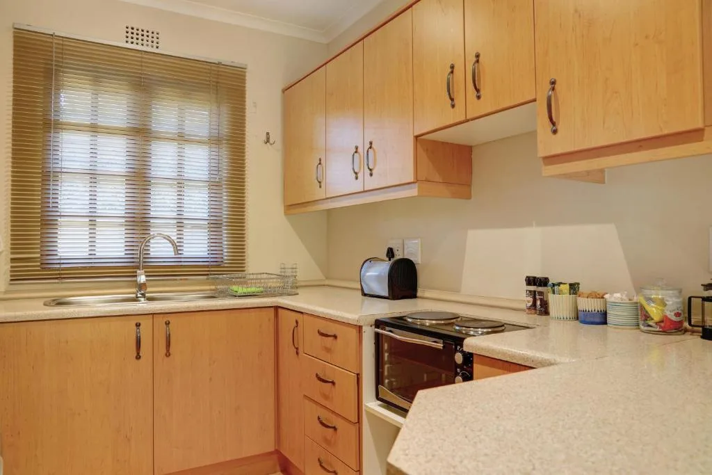 Bright kitchen with wooden cabinetry, stove, and granite countertops