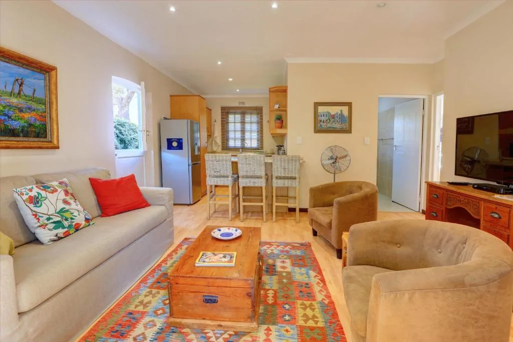 Open-plan lounge with cream sofa, tan armchairs, wooden coffee table, and TV