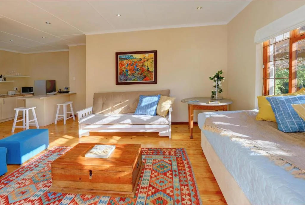 Spacious open-plan lounge with sofa, beds, and kitchen area visible