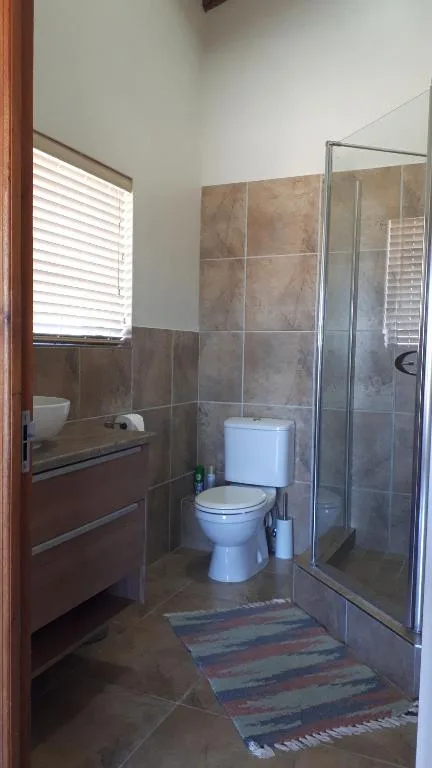 Modern bathroom with tiled shower enclosure, toilet, and vanity sink