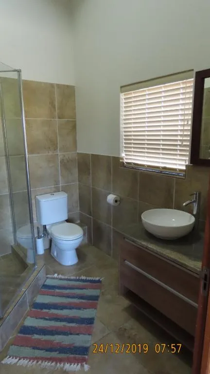 Bathroom with toilet, shower enclosure, round sink vanity, and window