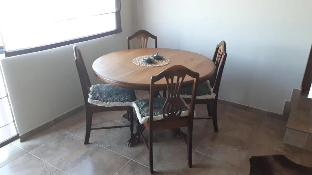 Round wooden dining table with four chairs and natural light