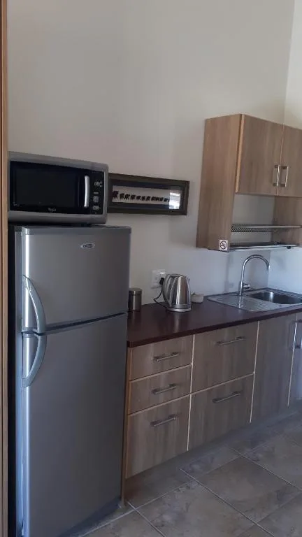 Compact kitchen with stainless steel fridge, microwave, and wooden cabinetry