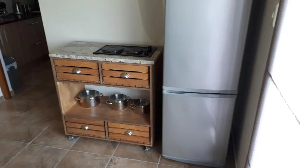 Kitchen counter with wooden cabinetry, stainless steel refrigerator, and cookware