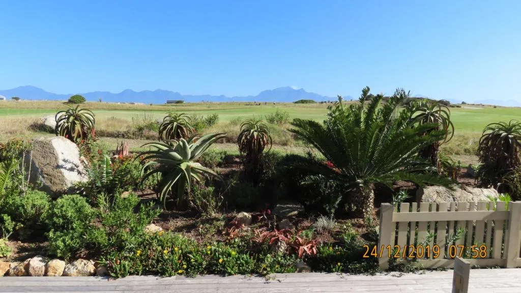 Mountain vista and farmland visible beyond manicured coastal garden landscape