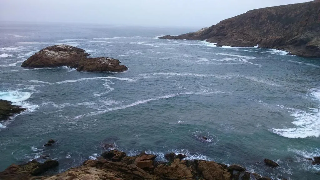 Dramatic rocky coastline with turquoise ocean waves and distant cliffs