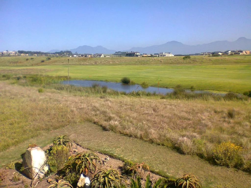 Expansive rural landscape with mountains, wetland pond, and distant properties