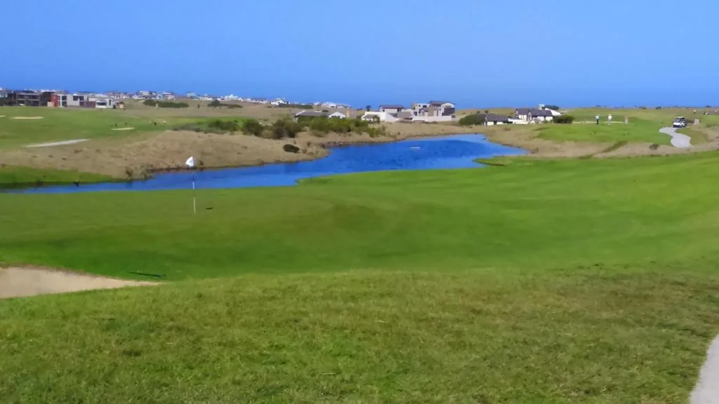 Scenic coastal property view with lagoon, green fields, and distant ocean horizon
