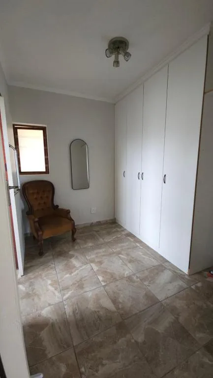 Spacious bedroom with white built-in wardrobes and tiled flooring