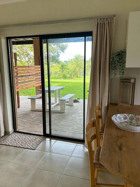 Expansive green garden and lawn visible through open sliding glass doors
