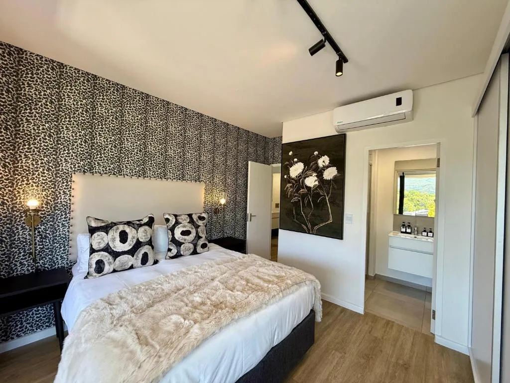 Modern bedroom with patterned accent wall, queen bed, and en-suite bathroom visible