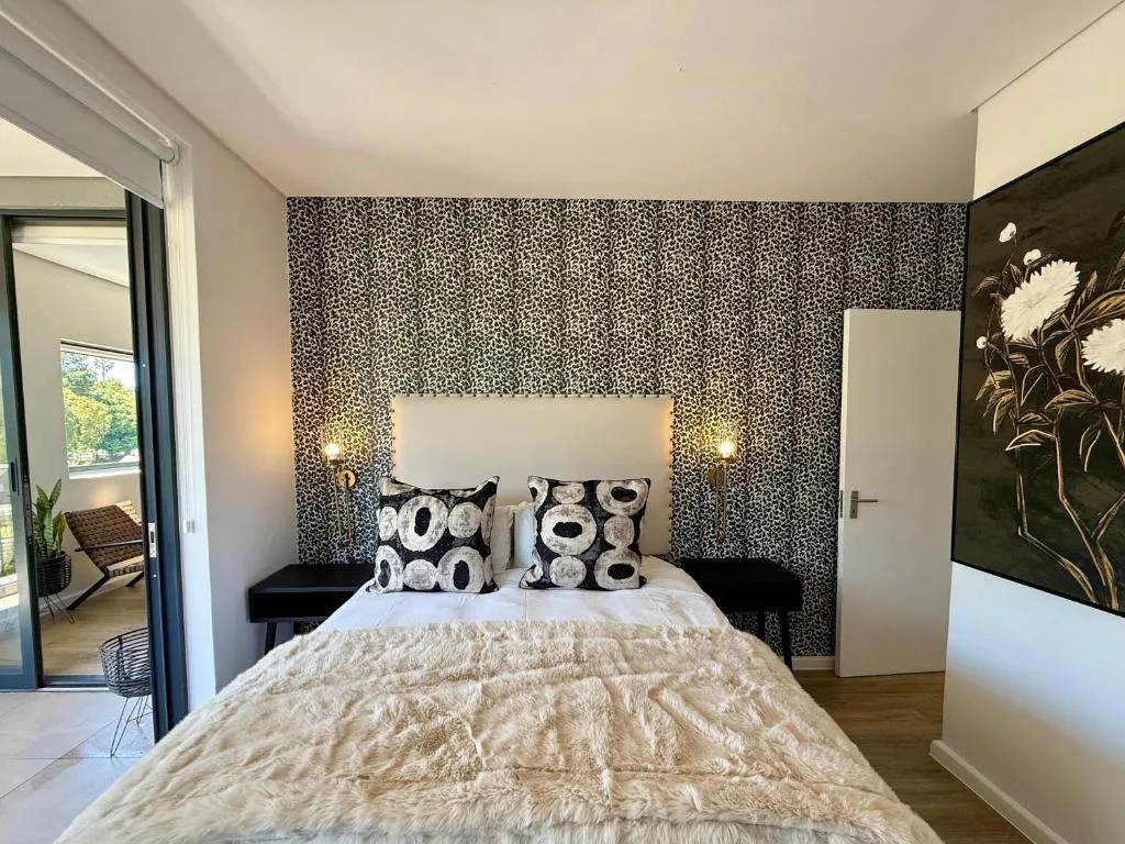 Modern bedroom with patterned accent wall, white headboard, and deck access