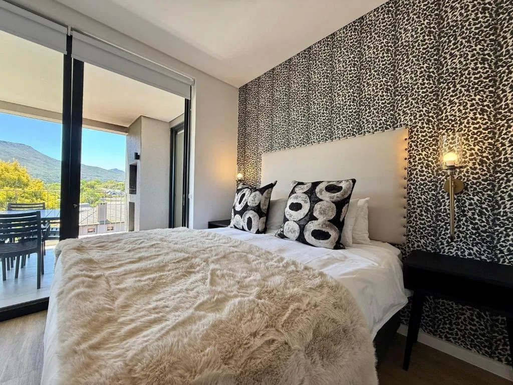 Modern bedroom with leopard-print accent wall and mountain views through sliding doors