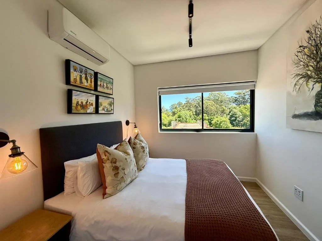 Bedroom with queen bed, wall art, air conditioning, and garden views through windows