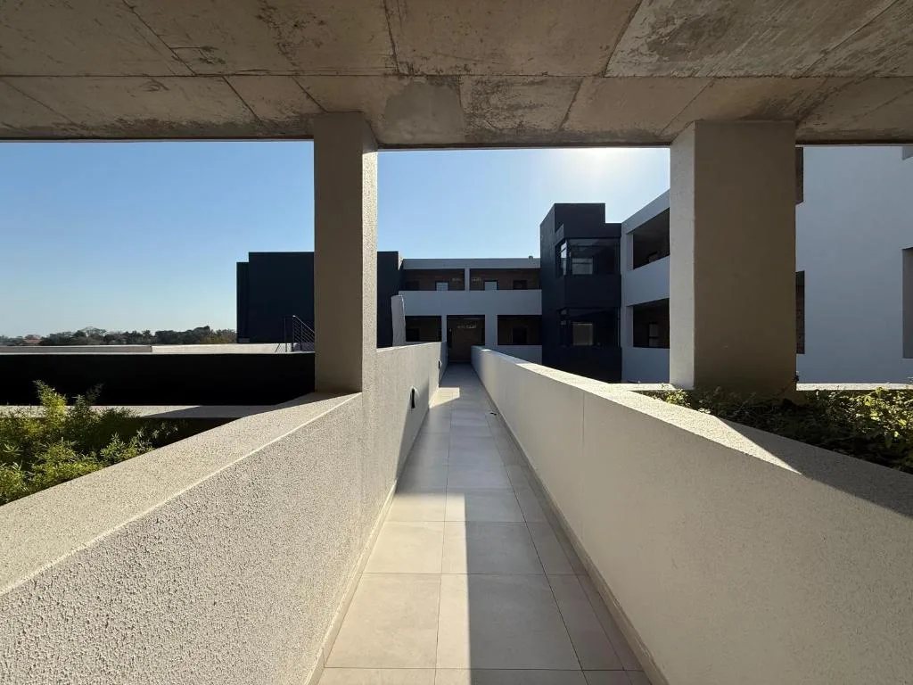 Modern concrete pathway with architectural building facade and open sky
