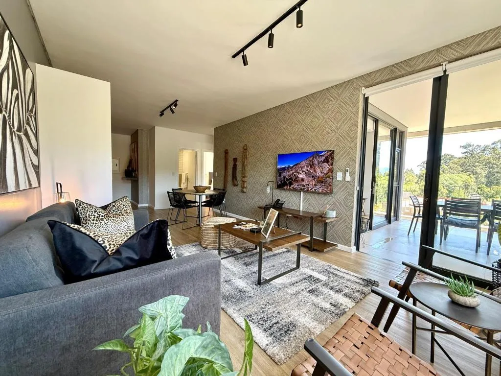 Modern lounge with gray sofa, patterned wallpaper, and outdoor deck access