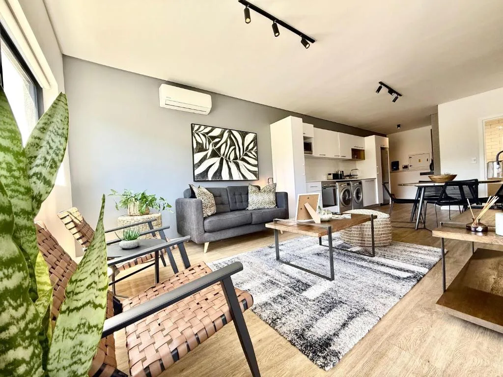 Modern open-plan lounge with gray sofa, wooden furniture, and kitchen visible