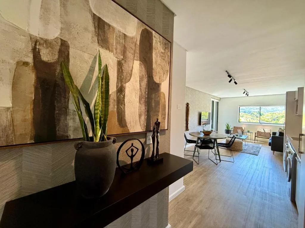 Modern lounge with artwork, decorative objects, and garden view through windows