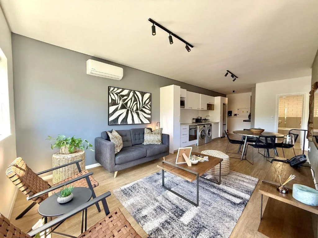 Modern open-plan lounge with gray sofa, dining area, and kitchen visible