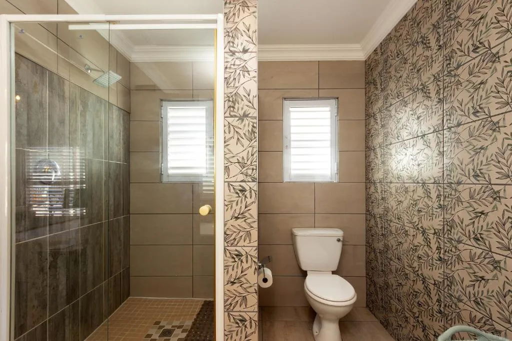 Modern bathroom with walk-in shower, toilet, and decorative tile walls