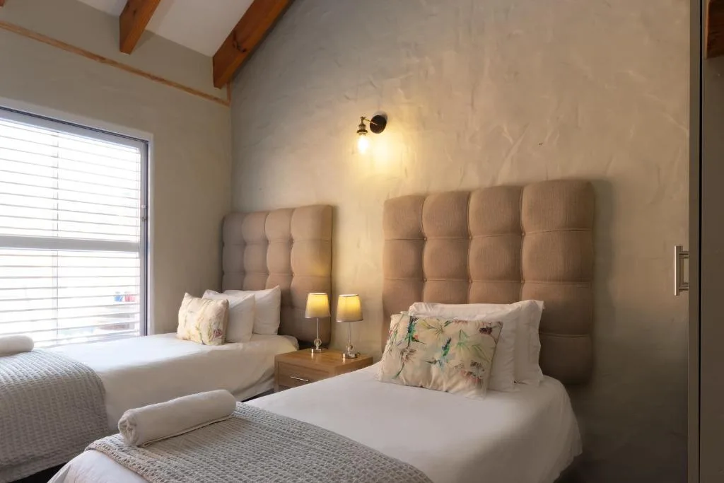 Twin beds with upholstered headboards and soft bedside lighting