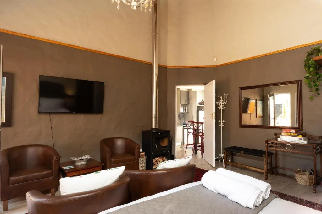 Spacious bedroom with two beds, leather seating, fireplace, and TV