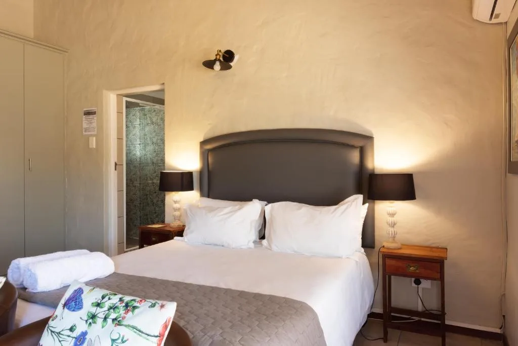 Spacious bedroom with double bed, dark headboard, bedside lamps and en-suite bathroom