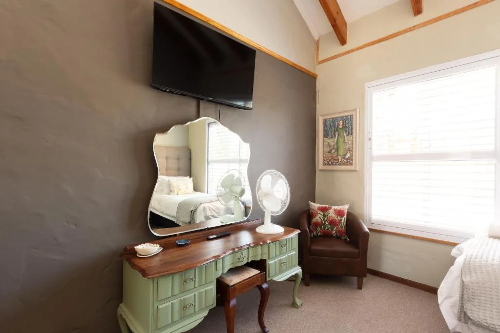 Bedroom with vanity mirror, wall-mounted TV, and exposed wooden beams