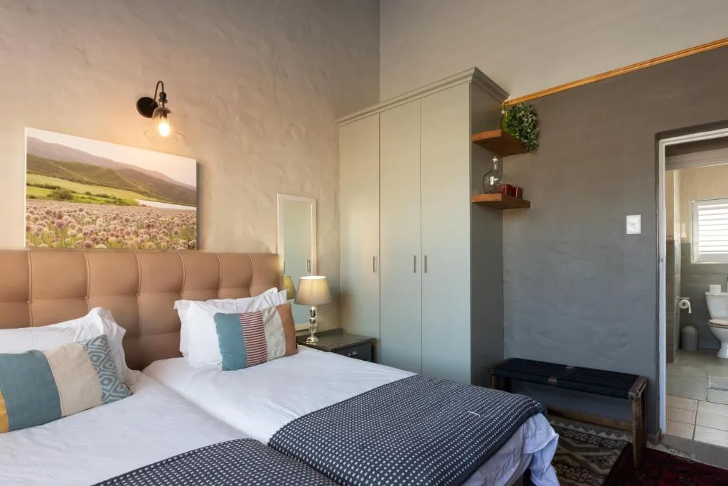 Modern bedroom with twin beds, padded headboard, and en-suite bathroom access