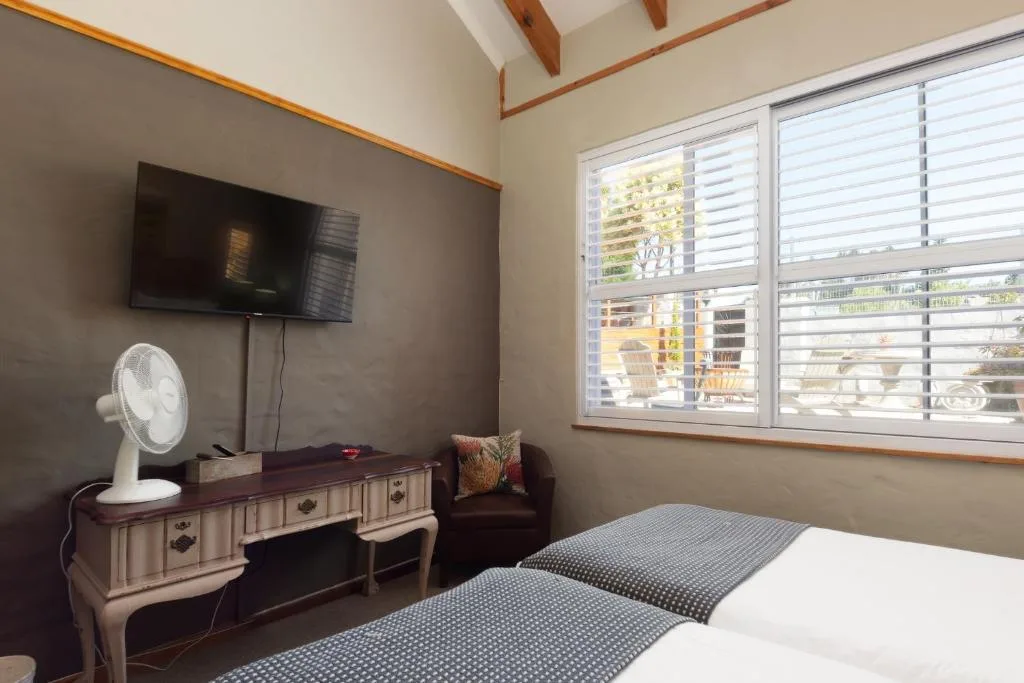 Bright bedroom with twin beds, TV, desk, and large windows overlooking town