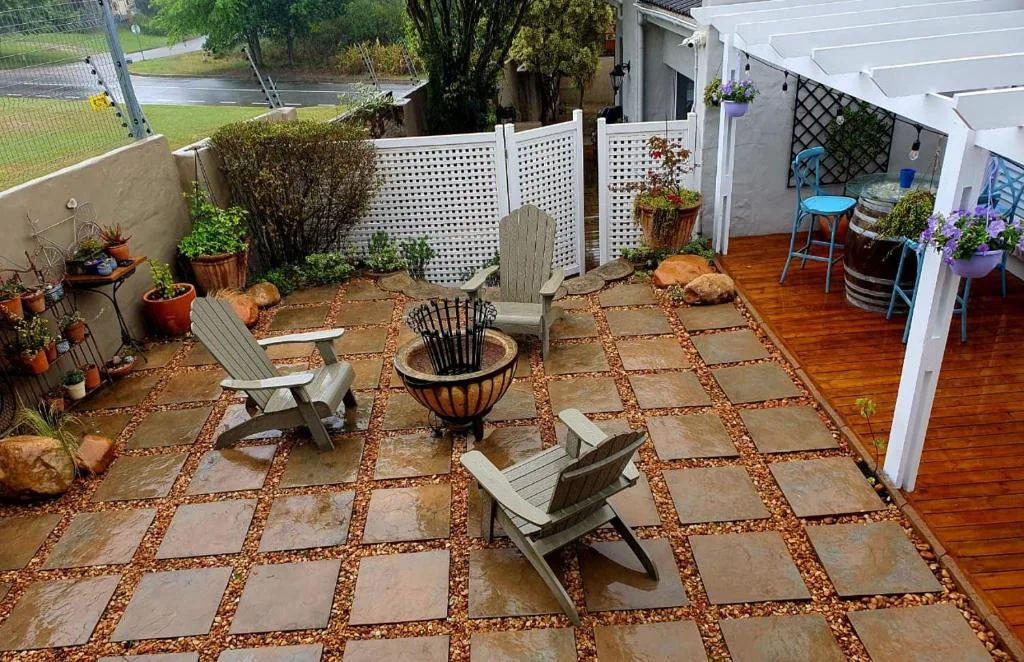 Paved outdoor patio with Adirondack chairs, fire pit, and potted plants