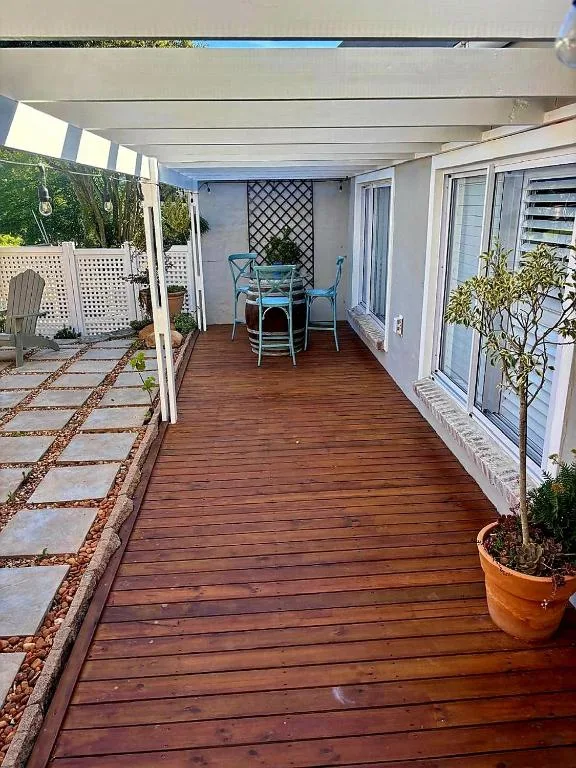 Covered wooden deck with dining furniture and garden access